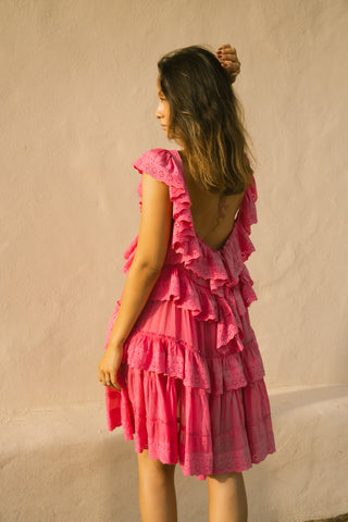 Woman wearing a pink ruffled dress against a beige wall